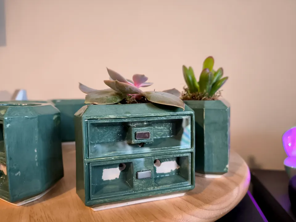 A green Vertical Ceramic Nest prototype from the front, with a succulent in the planter